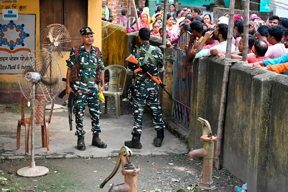 Paramilitary soldiers stand guard as people queue at a polling station to cast their votes in West Bengal’s ‘Panchayat’ elections held on the outskirts of Kolkata on July 8, 2023. AFPPIX