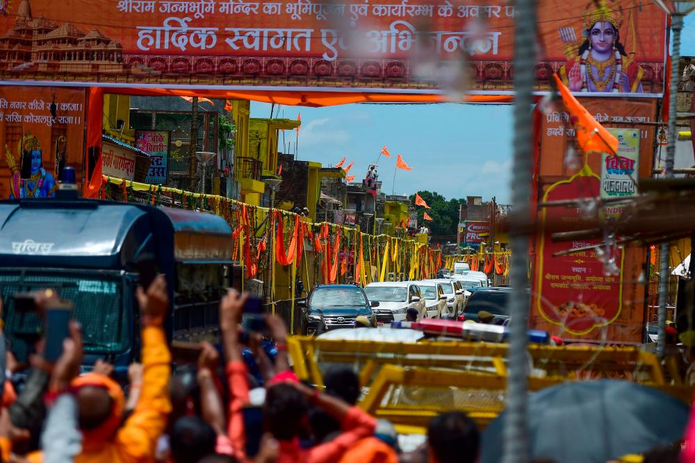 People wave India's Prime Minister's convoy arrives outside Hanuman Gadhi temple before the groundbreaking ceremony of the Ram Temple in Ayodhya on Aug 5, 2020. — AFP