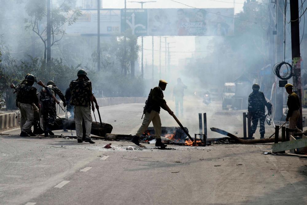 Police officers remove a burning blockade from a road in Guwahati on December 12, 2019. - AFP