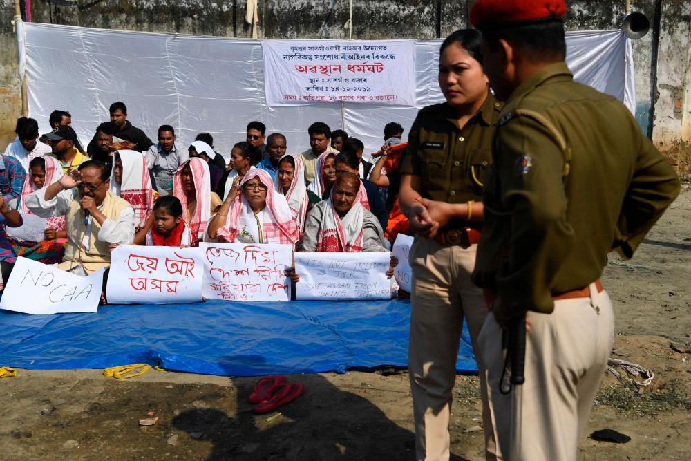 Police stand next to protestors taking part in a demonstration against the Indian government's Citizen Amendement Bill (CAB) in Guwahati on December 14, 2019. - AFP