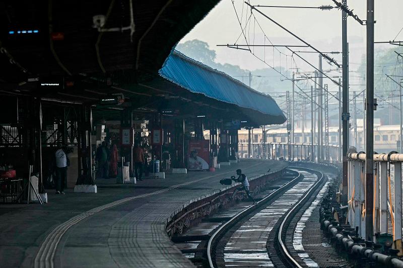 A passenger walks across a railway track at the New Delhi railway station in New Delhi on February 16, 2025. At least 15 people died during a stampede at a railway station in India's capital late on February 15 when surging crowds scrambled to catch trains to the world's largest religious gathering, a medical official told AFP. - Sajjad HUSSAIN / AFP