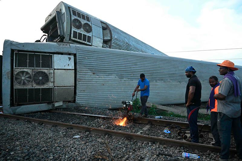 India railway workers restore the site following derailing of several coaches of the Mysuru-Darbhanga Bagmati Express train after collision with a goods train at the Kavaraipettai Railway Station, located near Gummidipundi, some 40km north of Chennai on October 12, 2024. - R. Satish BABU / AFP