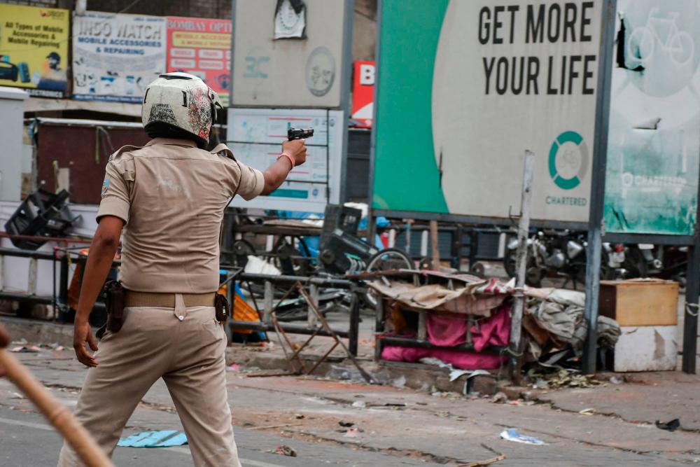 A policeman aims a handgun at demonstrators during a protest against former India's Bharatiya Janata Party spokeswoman Nupur Sharma and her remarks about Prophet Mohammed, in Ranchi on June 10, 2022. AFPPIX
