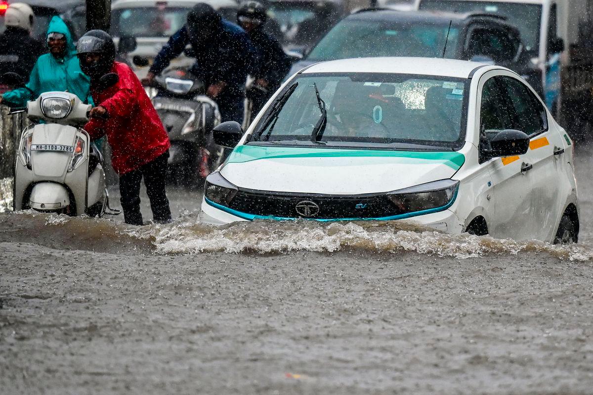 Vehicles wade through a flooded street during heavy rain showers in Mumbai on August 18, 2025. (Photo by Punit PARANJPE / AFP)