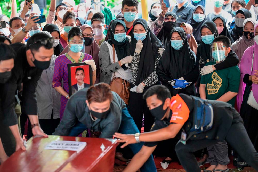 Aldha Refa (centre R-spotted top), the wife of Okky Bisma, a flight attendant and one of the 62 people aboard Sriwijaya Air flight SJ182 which crashed shortly after takeoff on January 9, looks toward the coffin with family members as they attend his funeral in Jakarta on January 14, 2021. / AFP / BAY ISMOYO