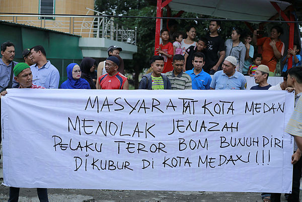 Indonesian residents hold a banner that reads “residents of Medan city reject the body of suicide bomber to be burried in Medan city”, in Medan on Nov 18, 2019. — AFP