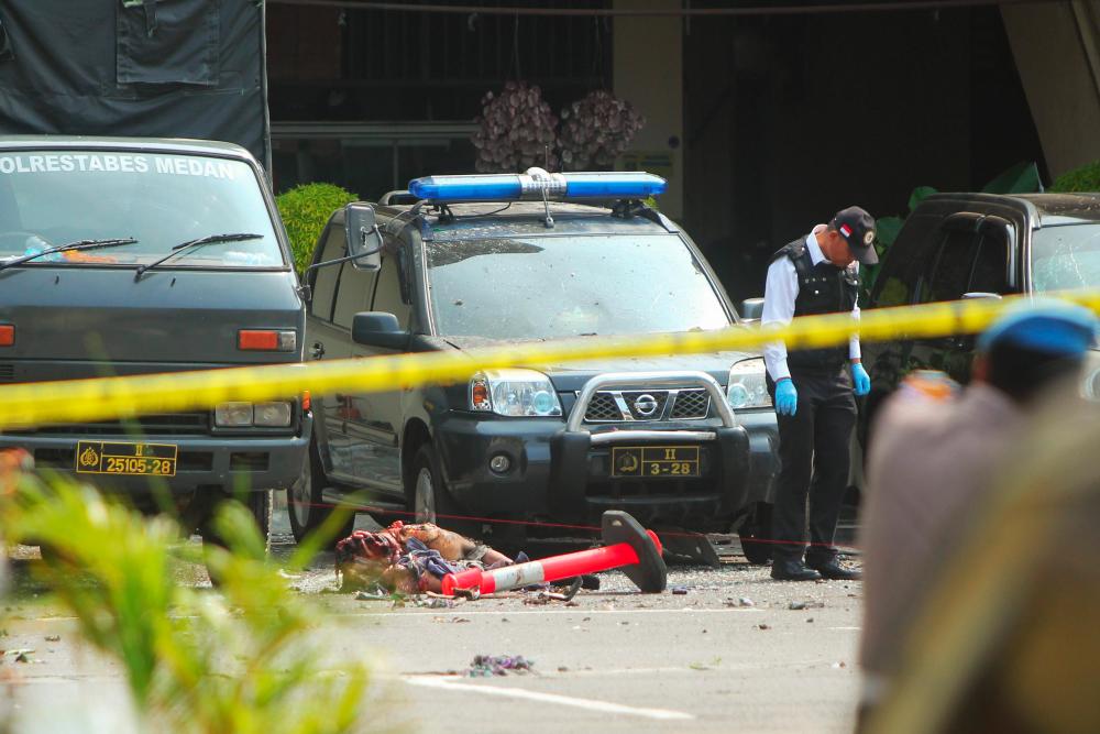 Indonesian police examine a body of a suspected suicide bomber at their headquarters in Medan, North Sumatra, on Nov 13 after a suicide attack occurred during their morning roll call. — AFP