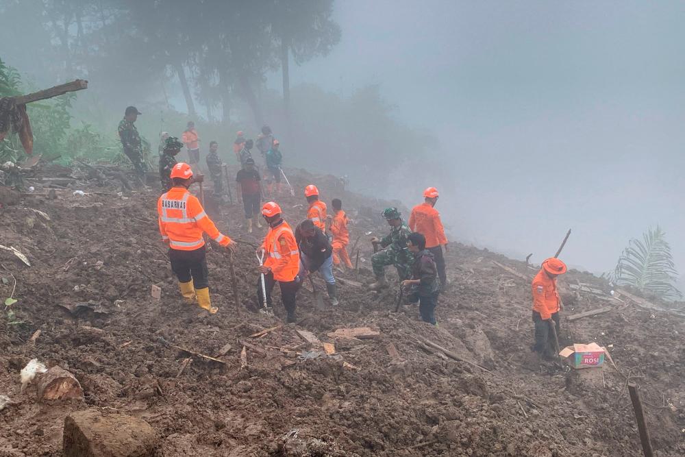 This handout photo taken and released on April 15, 2024 by the National Search and Rescue Agency (BASARNAS) shows rescuers searching for missing people at the site of a landslide that killed at least 18 people and left two missing in Tana Toraja, South Sulawesi/AFPPix