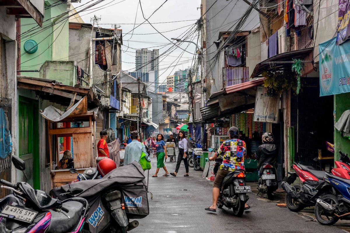 Residents living in a densely populated neighborhood walk along a street as they look for lunch at food stalls serving ready-to-eat meals in Jakarta on May 26, 2025.AFPpix