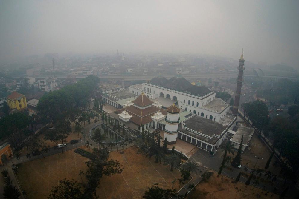 This aerial picture taken on September 20, 2019 shows haze covering the city of Palembang, South Sumatra. Indonesia is battling forest fires causing toxic haze across southeast Asia with aircraft, artificial rain and even prayer, President Joko Widodo said during a visit to a hard-hit area. — AFP