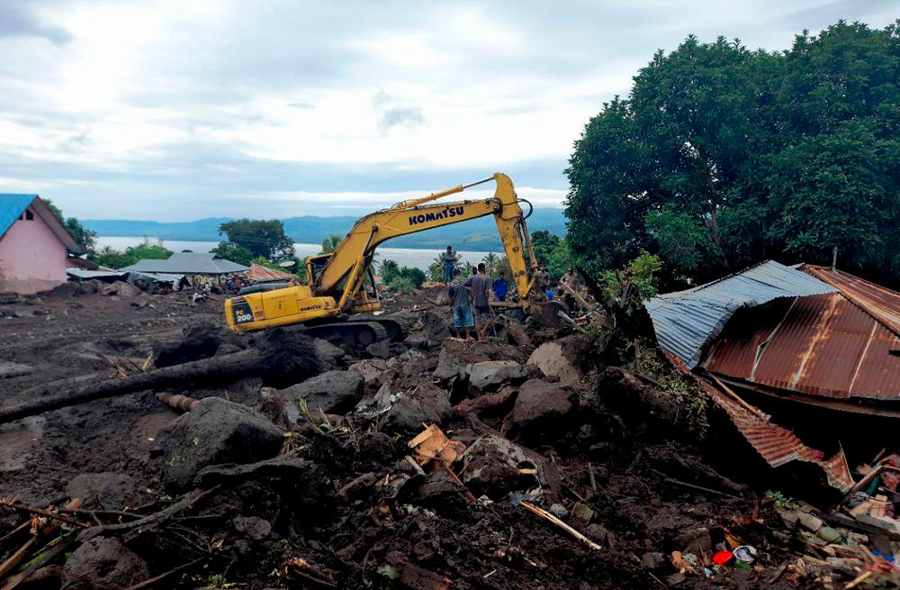 This picture taken on April 7, 2021 shows rescuers using diggers and shovels to extract mud-covered corpses from the debris in Lamanele village, East Flores, after torrehtial rains from Tropical Cyclone Seroja, one of the most destructive storms to hit the region in years, turned small communities into wastelands of mud. –AFP