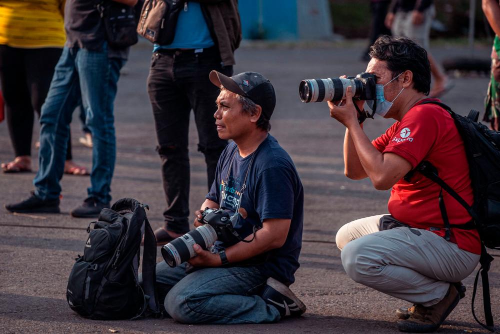 This picture taken on October 4, 2022 shows photographer Ari Bowo Sucipto (L) at work during aftermath coverage of the Kanjuruhan football stadium disaster, in Malang. AFPPIX