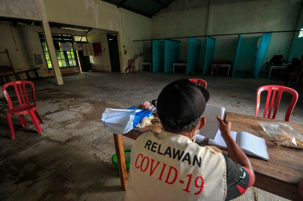 A volunteer keeps watch at a quarantine facility, a repurposed abandoned house believed by some locals to be haunted and used as a deterrent effect against those breaking social restrictions amid the COVID-19 coronavirus pandemic, at Sepat village in Sragen, Central Java, on April 21, 2020. — AFP