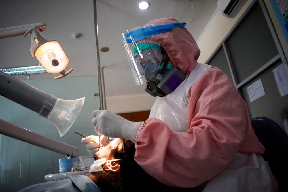 A dentist wearing full personal protective equipment amid the pandemic tends to her patient at a dental clinic in Bandung on January 19, 2022. AFPPIX