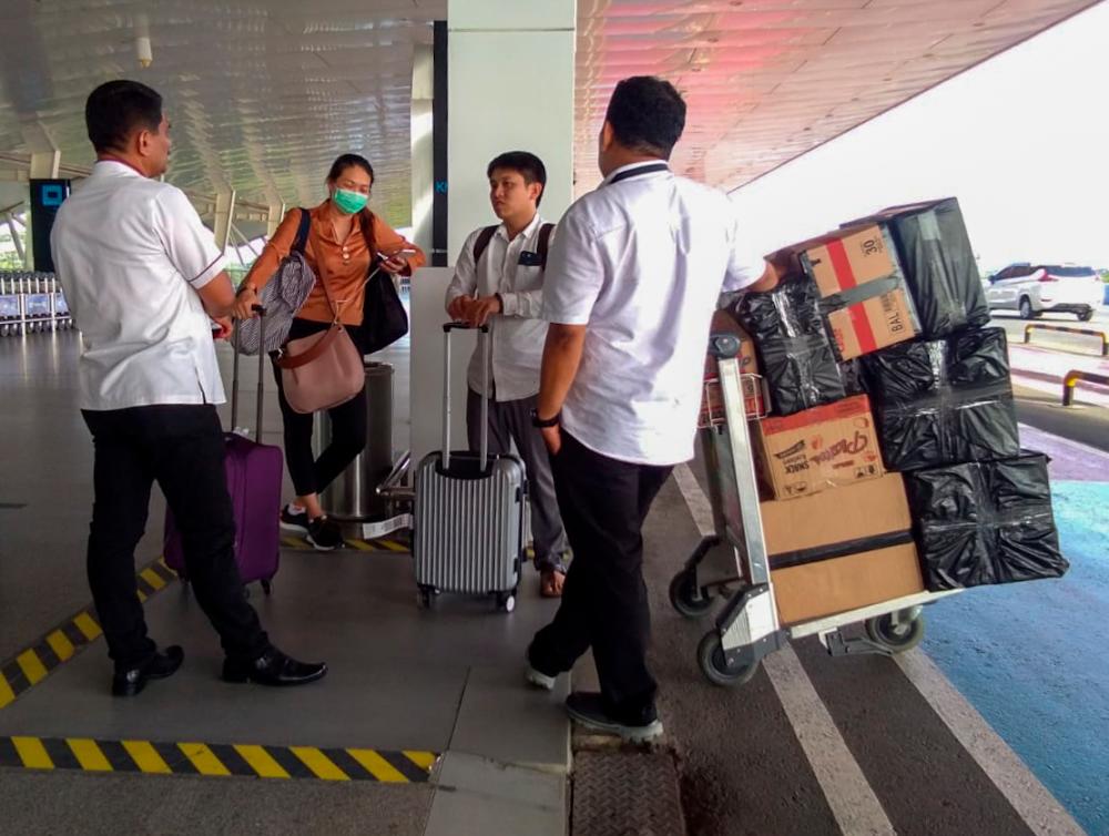 This picture taken on March 11, 2020 shows Indonesia authority officials questioning two Malaysians (C) at Medan Internasional airport, in Medan, North Sumatra, for allegedly trying to smuggle some 12,000 facemasks back home. - AFP