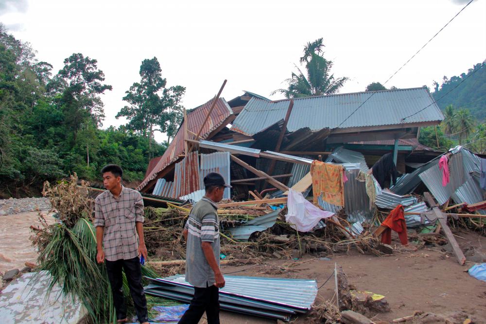 Villagers stand near a damaged house by a river after a flash flood at Pesisir Selatan in West Sumatra on March 10, 2024/AFPpix