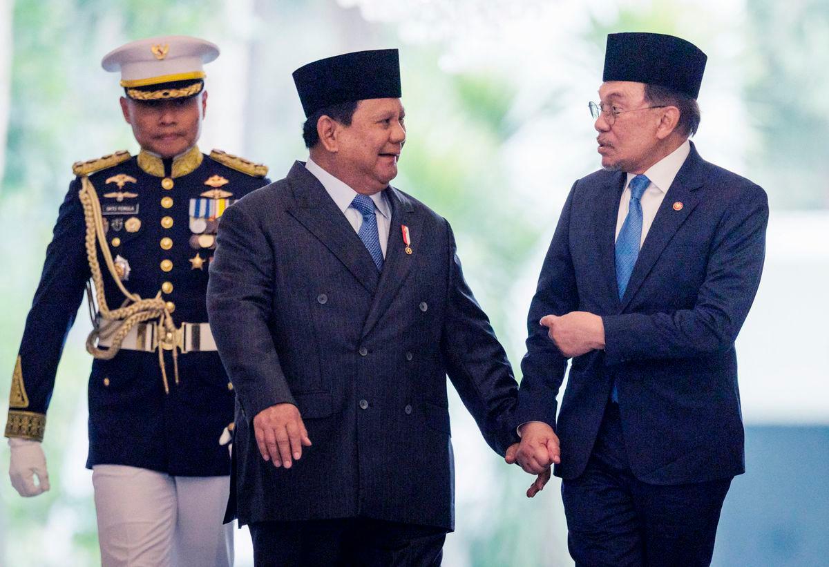 Malaysia’s Prime Minister Anwar Ibrahim (R) and Indonesia’s President Prabowo Subianto (C) walk together ahead of their bilateral meeting at the Presidential Palace in Jakarta on July 29, 2025. (Photo by Yasuyoshi CHIBA / AFP)