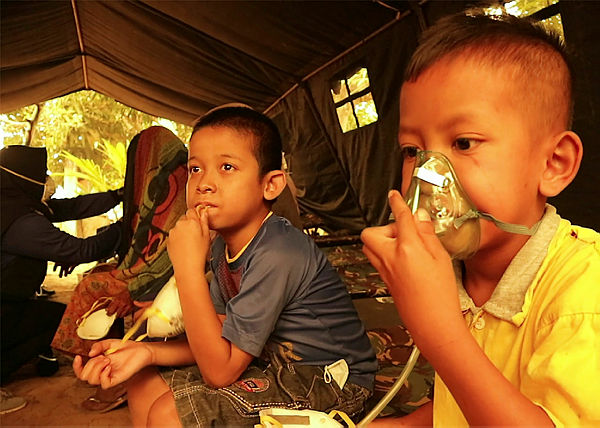 Children get a dose of oxygen from a Red Cross volunteer at a village in Jambi today. — AFP