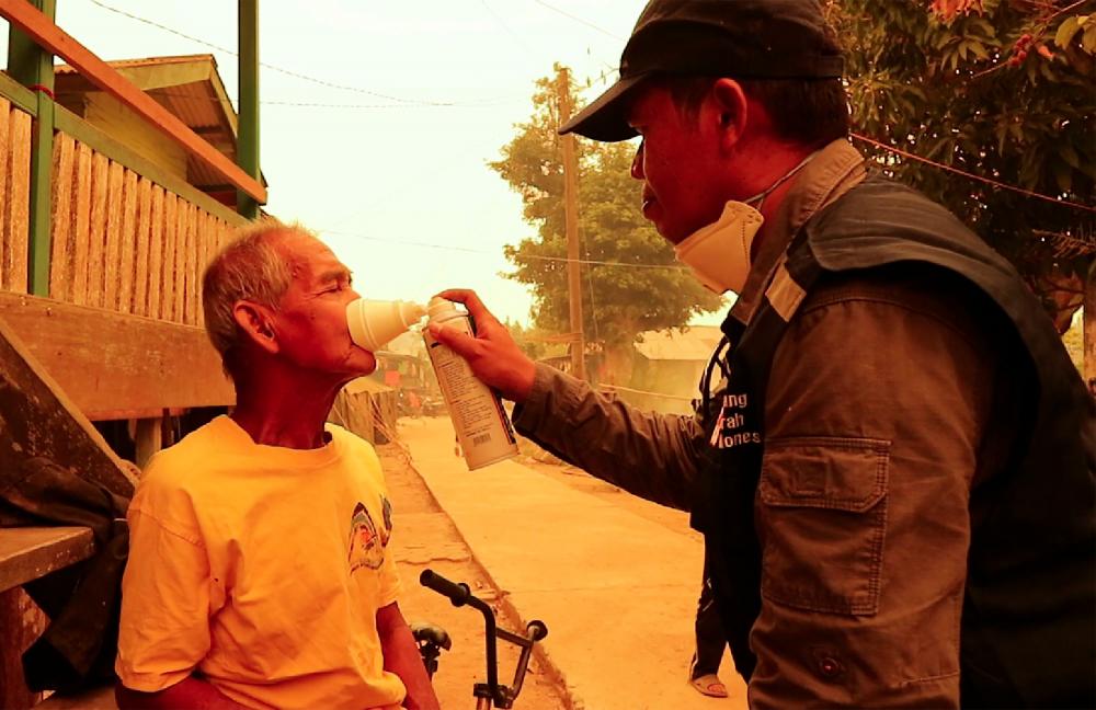 An elder villager gets a dose of oxygen from a Red Cross volunteer outside his home in Jambi on Sept 24, 2019. — AFP