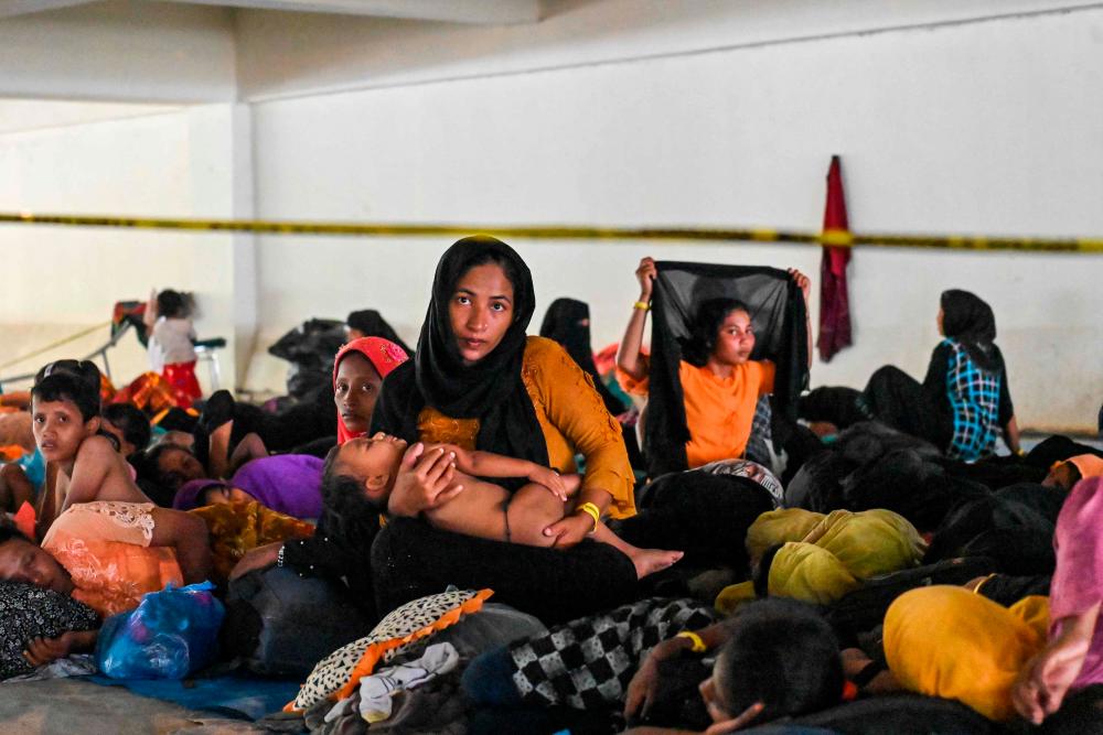 Rohingya refugees rest in the basement parking area of a government building after villagers rejected their relocated camp, in Banda Aceh on December 13, 2023/AFPPix