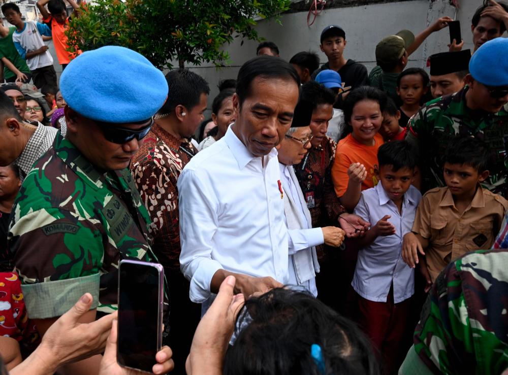Indonesian President Joko Widodo (C) and his running mate Ma'ruf Amin (center R) speak with residents in a neighbourhood in Jakarta on May 21, 2019. - AFP