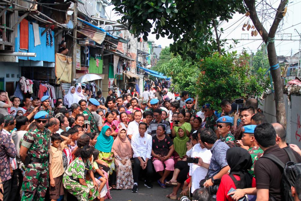 Indonesian President Joko Widodo (C) sits with local residents while visiting a neighbourhood in Jakarta on May 21, 2019. - AFP