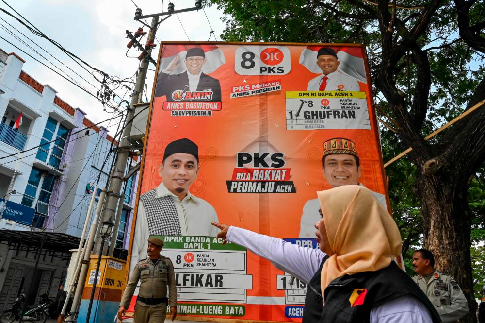 Members of the public order service (Satpol PP) remove election campaign banners at the end of campaign day in Banda Aceh on February 11, 2024, ahead of Indonesia’s upcoming general election scheduled to be held on February 14/AFPPix