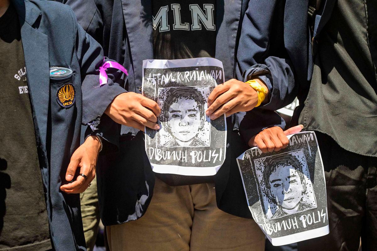Demonstrators hold portraits of Affan Kurniawan, a motorcycle taxi driver who was run over by a police Mobile Brigade Corps or ‘Brimob’ armoured vehicle on August 28, during a protest in front of the Regional Police headquarters in Surabaya on August 30, 2025. (Photo by JUNI KRISWANTO / AFP)