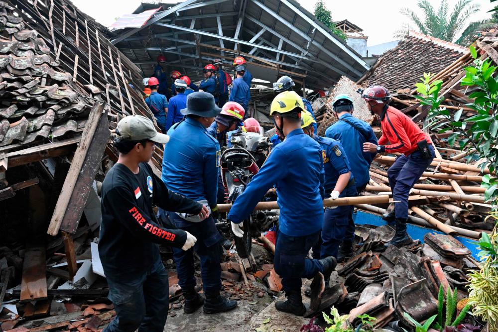 Rescue personnel remove a motorcyle as they work to find a missing child believed to be trapped in the rubble of a collapsed house at Cugenang in Cianjur, West Java on November 24, 2022, following a 5.6-magnitude earthquake on November 21. AFPPIX