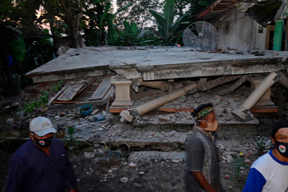 Villagers walk past a collapsed house at Sidorenggo village, in Malang, East Java on April 10, 2021 after a 6.0 magnitude earthquake struck off the coast of Indonesia’s Java island. - AFP
