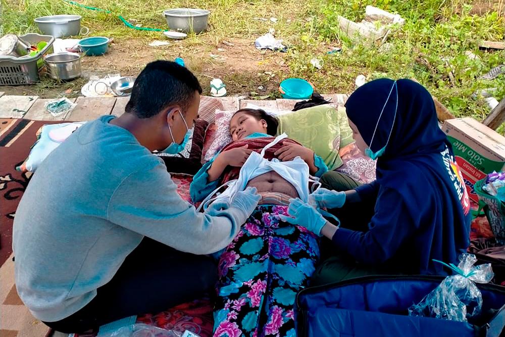 An injured woman is treated in a makeshift hospital in Majene on January 17, 2021, after a 6.2-magnitude earthquake rocked Indonesia’s Sulawesi island. / AFP / Aswan Aprianto