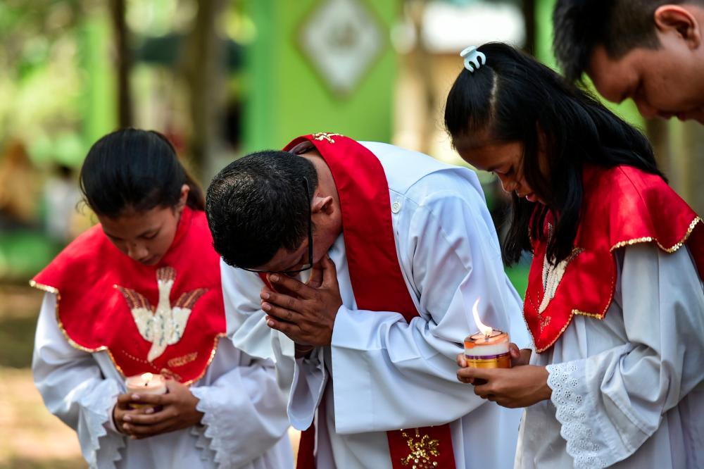 People pray to mark the 15th anniversary when an earthquake and resulting tsunami killed at least 170,000 people in the country and thousands of others in neighbouring countries, at a cemetery containing mass graves in Ulee Lheue, Banda Aceh on Dec 26. — AFP