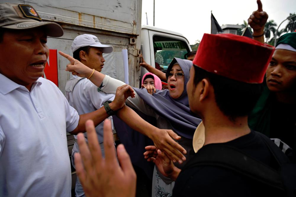Protesters (R) argue with plain-clothed police (L) during a rally near the constitutional court in Jakarta on June 26, 2019, a day before the court reads their decision on defeated presidential challenger’s claim that Indonesia’s 2019 election was rigged, allegations that spawned deadly rioting in May. — AFP