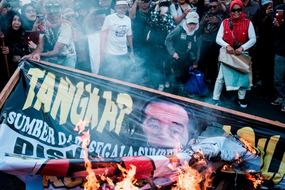 Demonstrators burn a billboard with a portrait of Indonesia’s President Joko Widodo during a protest against the results of the recent presidential election as the Constitutional Court rules on the petitions of ex-presidential candidates in Jakarta on April 22, 2024/AFPPix