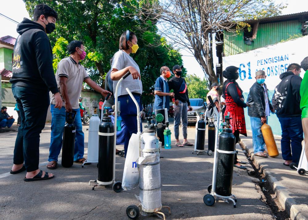 People lining up outside a factory to get their oxygen cylinders refilled amid a surge of Covid-19 cases in Jakarta on Monday. Indonesia has imposed broad restrictions on Java and Bali islands and added more measures last week in several other regions. – REUTERSPIX