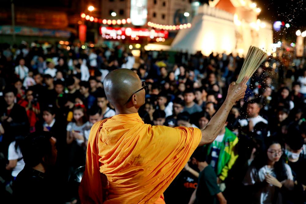 A buddhist monk sprinkles holy water as people pray for victims who died in mass shooting, involving a Thai soldier on a shooting rampage, in Nakhon Ratchasima, Thailand February 9, 2020. - Reuters