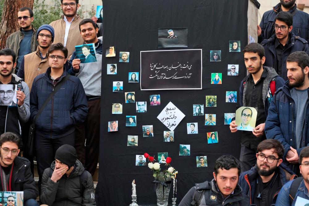 Iranian students hold pictures of victims during a memorial for the passengers of the Ukraine plane crash, in University of Tehran on January 14, 2020. - AFP
