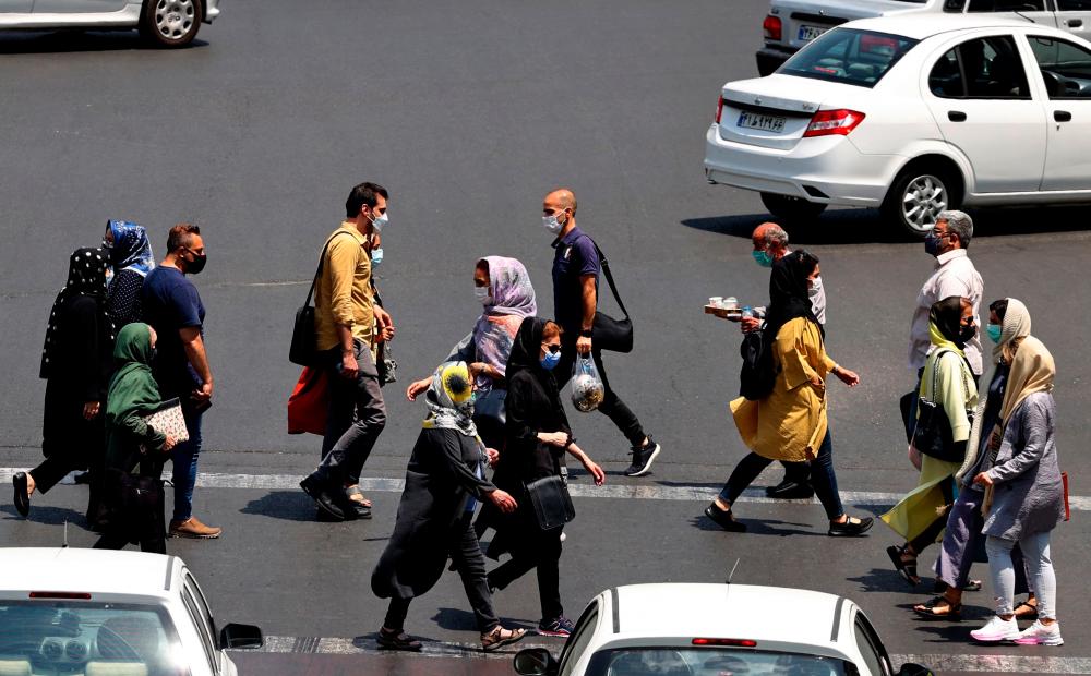 Iranians, mask-clad due to the coronavirus pandemic, cross a street in the capital Tehran, on July 3, 2021. — AFP