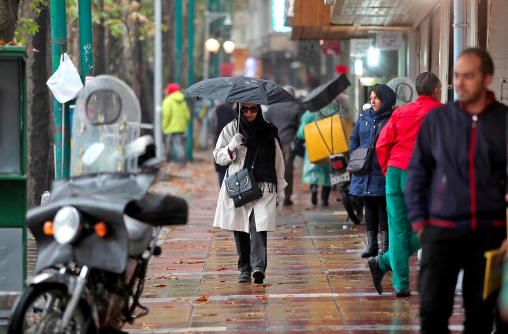 Iranians walk past stores in the Tajrish Bazaar in the capital Tehran on Nov 18. — AFP