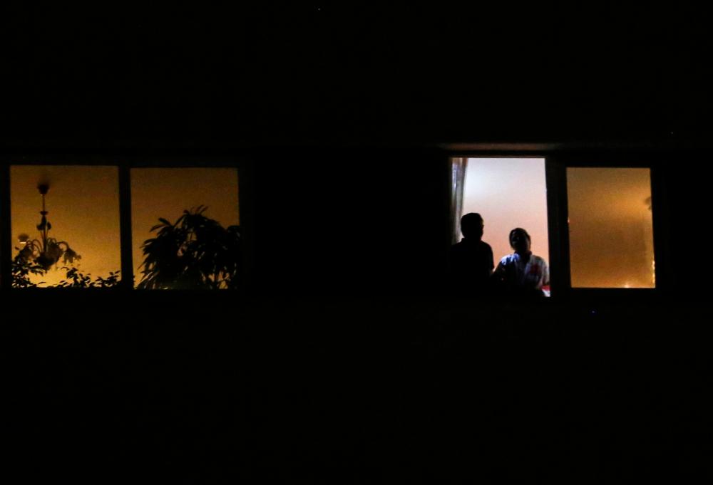 A couple look out of a window during confinement at home due to the Covid-19 coronavirus pandemic in the Iranian capital Tehran, on April 7, 2020. — AFP