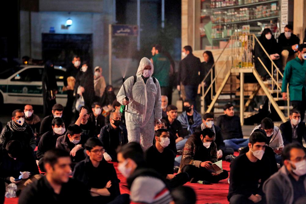 Iranians, some wearing face masks against the Covid-19 coronavirus, attend Laylat al-Qadr prayers, one of the holiest nights during the Muslim fasting month of Ramadan, outside a mosque in the Tehran, on May 13, 2020. — AFP