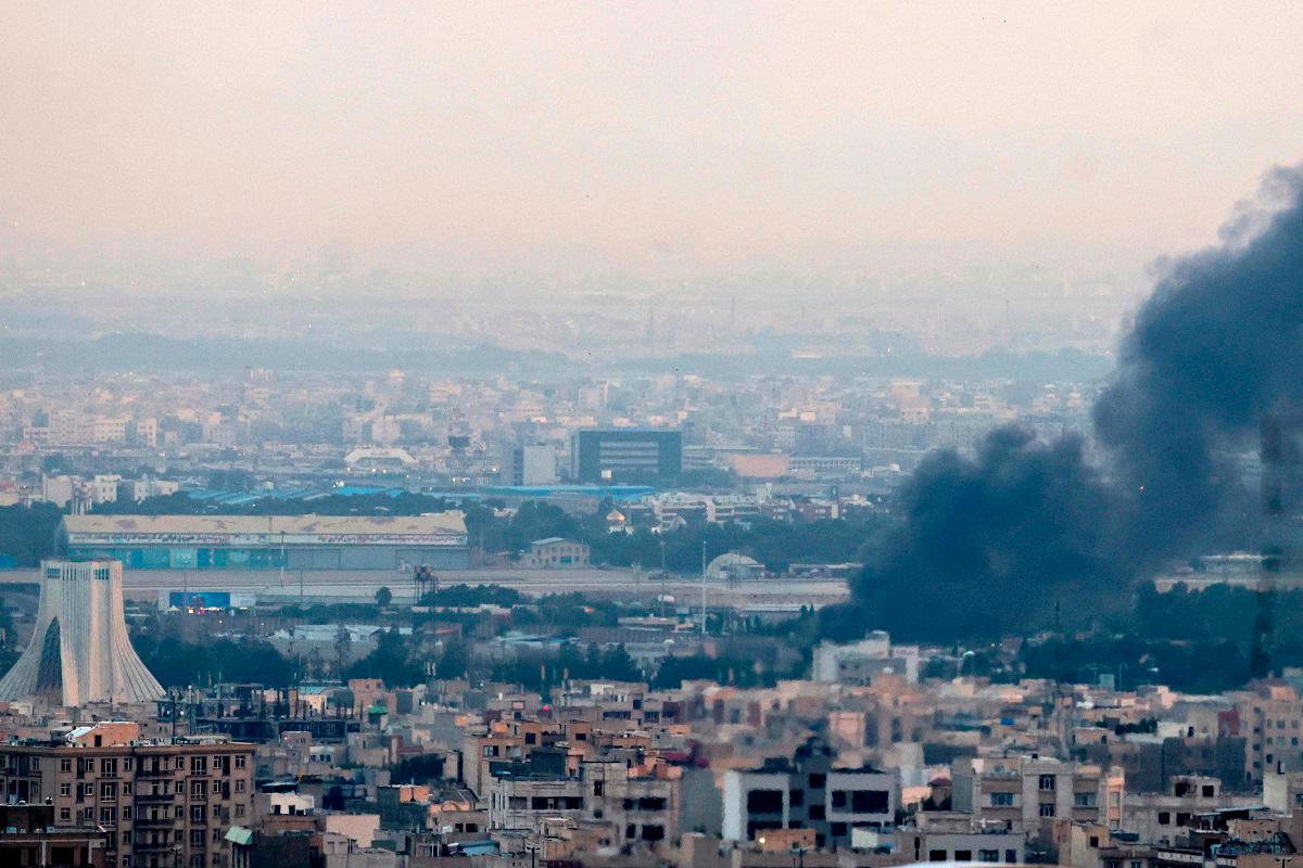 Smoke billows from a site near the Azadi Tower (L) in central Tehran, as fighting between Israel and Iran continues on June 16, 2025. Israel and Iran traded deadly fire on June 16 in their most intense confrontation in history, fuelling fears of a drawn-out conflict that could engulf the Middle East. - ATTA KENARE / AFP