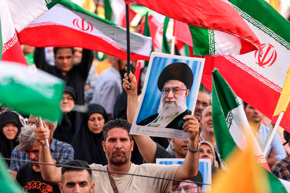 An Iranian man holds a portrait of supreme leader Ayatollah Ali Khamenei as people celebrate a ceasefire between Iran and Israel at Enghlab Square in the capital Tehran on June 24, 2025. - ATTA KENARE / AFP
