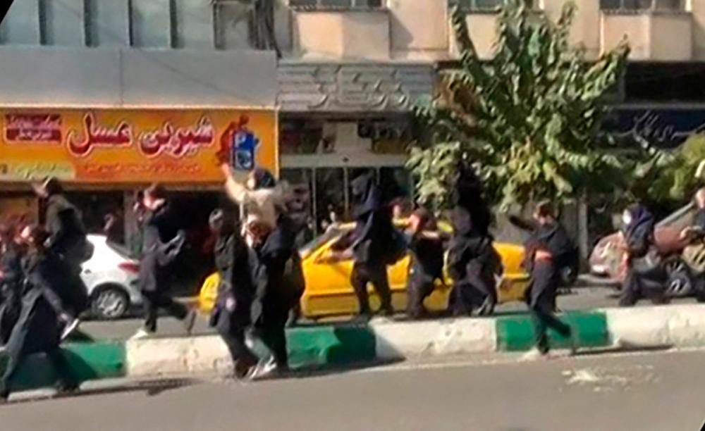 This grab taken from a UGC video made available on the ESN platform on October 12, 2022 shows Iranian students, some without headscarves, shouting “Death to the dictator” as they march in central Tehran. AFPPIX