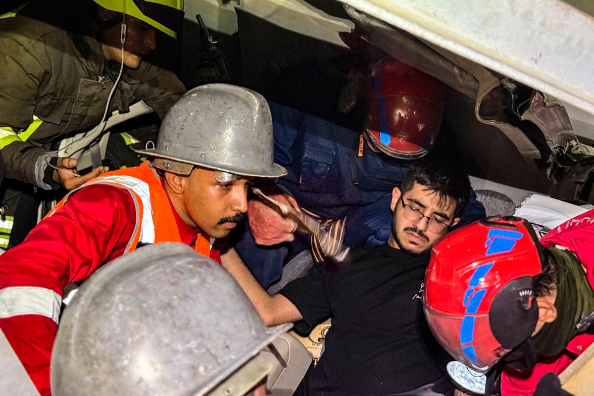 Rescuers retrieve a man from the wreckage of a section of a bridge under construction after it collapsed, killing two people and injuring others, in Karbala in southern Iraq late on September 6, 2025. Rescue workers laboured until morning to free those trapped in their vehicles under the twisted wreckage of the bridge on the main Karbala-Baghdad road. (Photo by Salman AMIN / AFP)