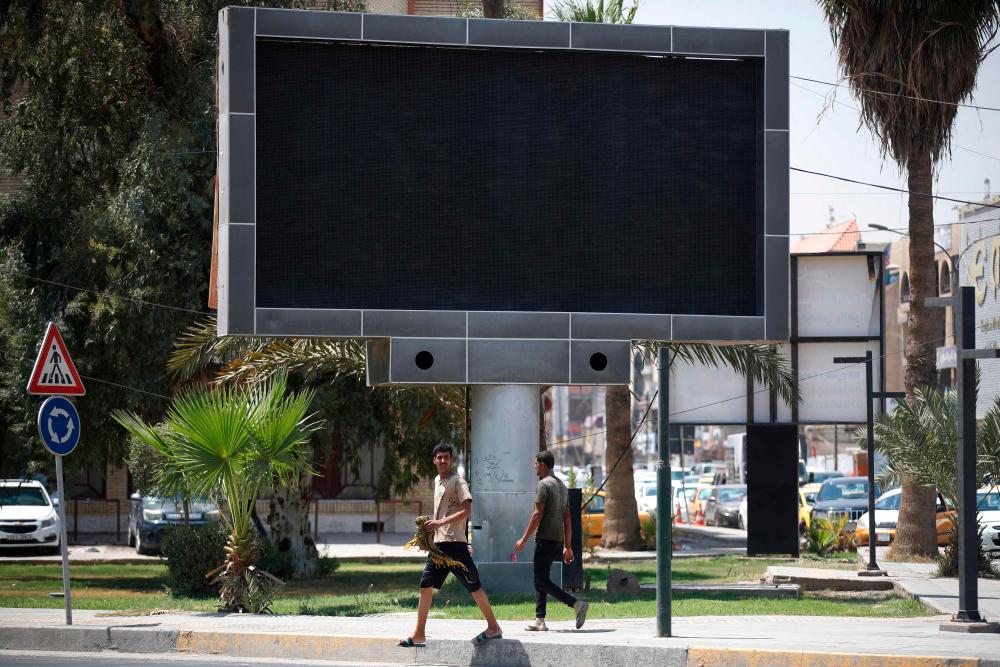Vehicles drive past a shut advertisement screen at the Uqba Bin Nafia square in Baghdad on August 20, 2023. AFPPIX