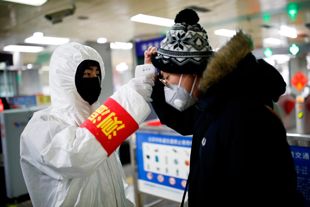 A staff member checks the temperature of a passenger entering a subway station, as the country is hit by an outbreak of the new coronavirus, in Beijing, China January 28, 2020. - Reuters