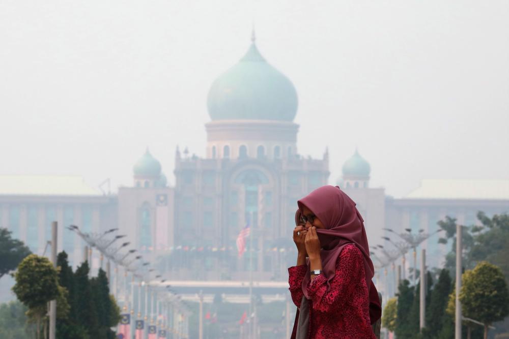 A woman covers her face with a scarf in front of the Malaysia's Prime Minister's office, which is shrouded in haze, in Putrajaya, Malaysia, September 17, 2019. - Reuters
