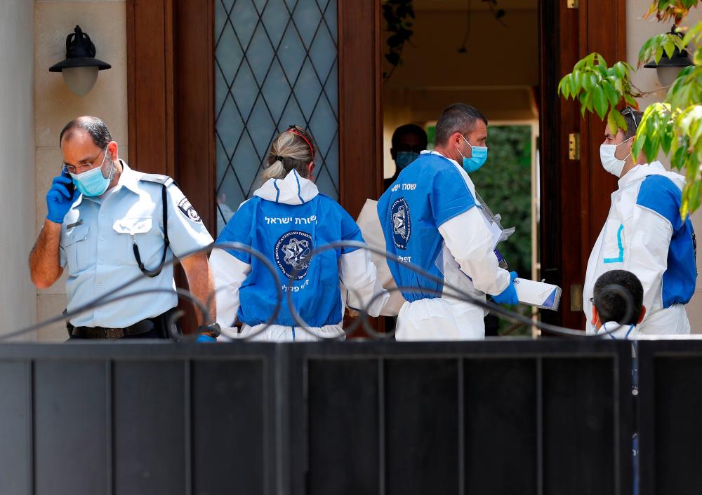 Police and forensic experts gather at the entrance to the residence of Israel's Chinese ambassador as forensic experts walk out after he was found dead on May 17, 2020. — AFP
