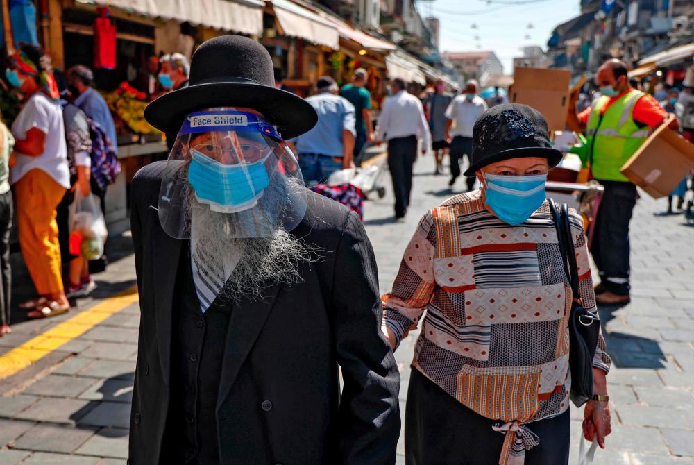 Shoppers, wearing protective masks due to the Covid-19 pandemic, walk at Mahane Yehuda market in Jerusalem on Sept 24, 2020, a day ahead a nationwide lockdown aimed at curbing a surge in coronavirus cases. — AFP